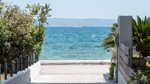A paved pathway leading to a coastal view with a clear sky and calm sea. - Amare Luxury Living Volos (Volos)