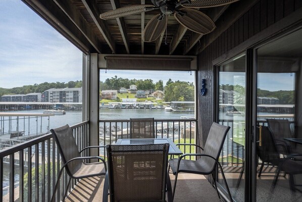 A balcony with a table and chairs, overlooking a marina with boats and buildings.