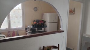 Eine Küche mit Mikrowelle, Kaffeemaschine und Topfpflanzen auf der Arbeitsfläche.