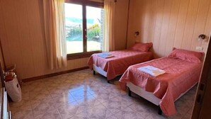 A room with two beds, a wooden ceiling, and a view through a sliding door. - LA 48 (El calafate)