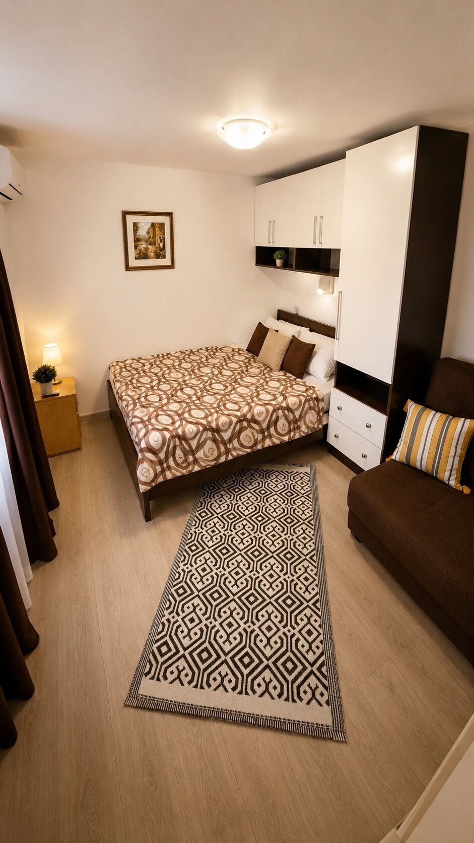 Une chambre à coucher comprenant un lit, un canapé, une armoire, une table de chevet avec une lampe et un tapis.