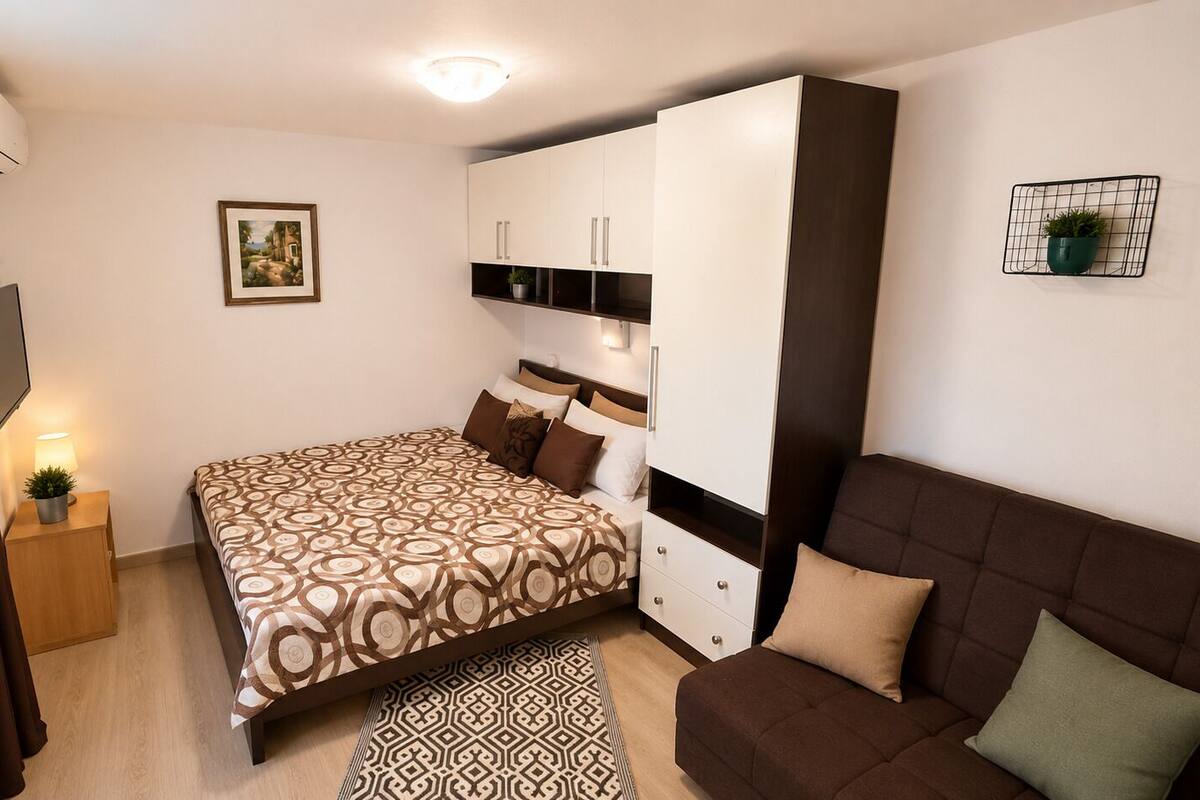 Un dormitorio con cama, sofá, televisión, armario y una mesita de noche.
