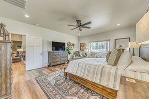 A spacious bedroom with a large bed, a ceiling fan, and a view of the outdoors through a window. - Hike, Golf, Ski & More! Spacious Ruidoso Home (Ruidoso)