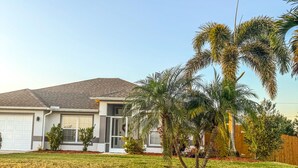 A residential house with a garage, a lawn, and a small palm tree. - 3 bedroom/ 2 bath/ pool/ spa
Located in NE Cape Coral (Cape Coral)