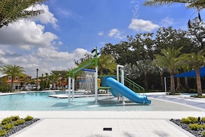 Une piscine avec un toboggan, entourée de palmiers et sous un ciel dégagé.
