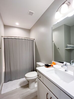 Une salle de bain moderne équipée de toilettes, d’un lavabo et d’un rideau de douche.