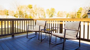Une terrasse en bois avec deux fauteuils à bascule et une petite table.