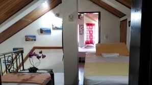 Un dormitori amb un llit, una taula petita i una cadira. Hi ha una finestra amb cortines i un quadre a la paret.