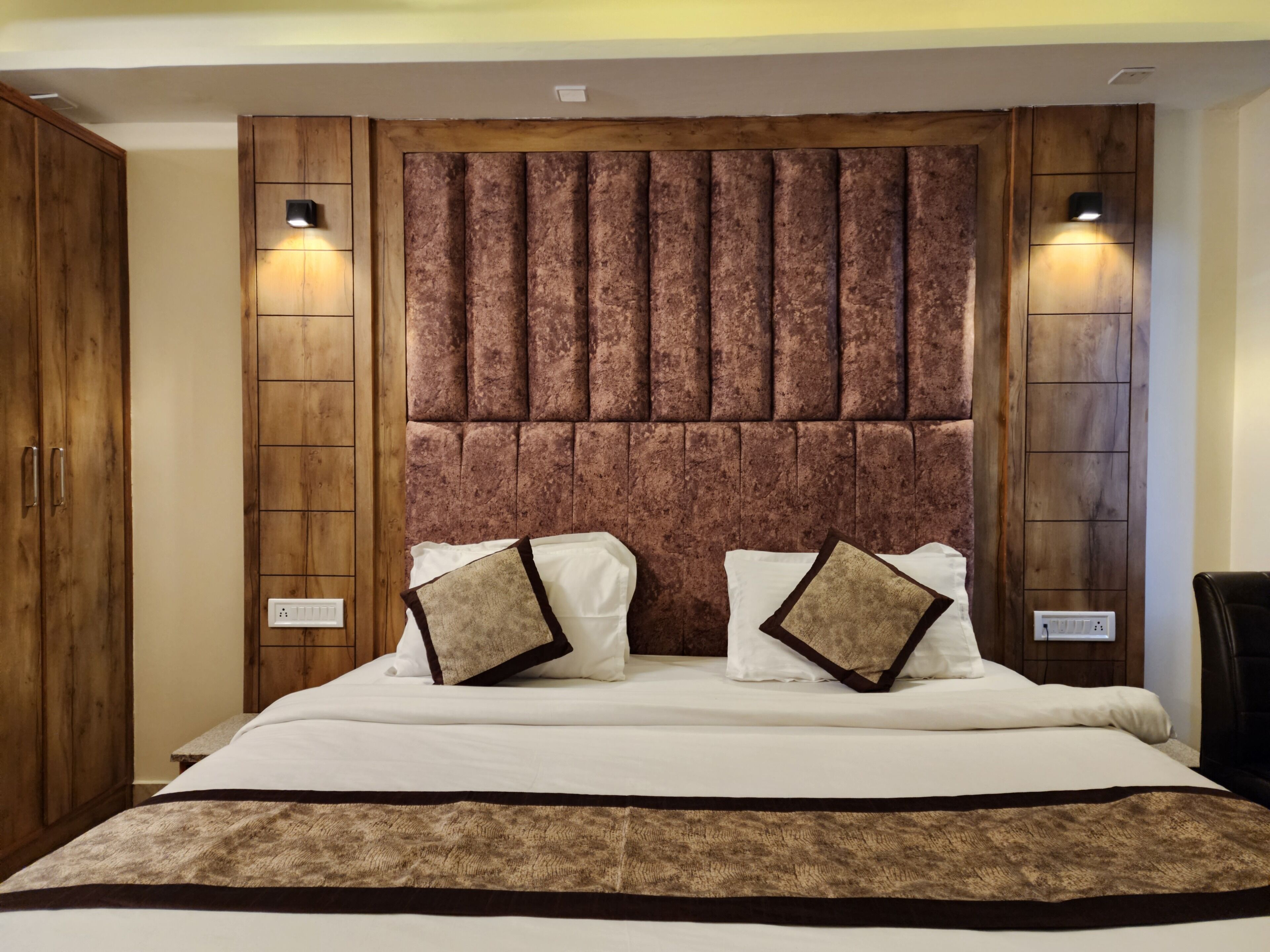 Ein Schlafzimmer mit einem großen Bett, einem Holzkopfstück, zwei Nachttischlampen und einem Kleiderschrank.