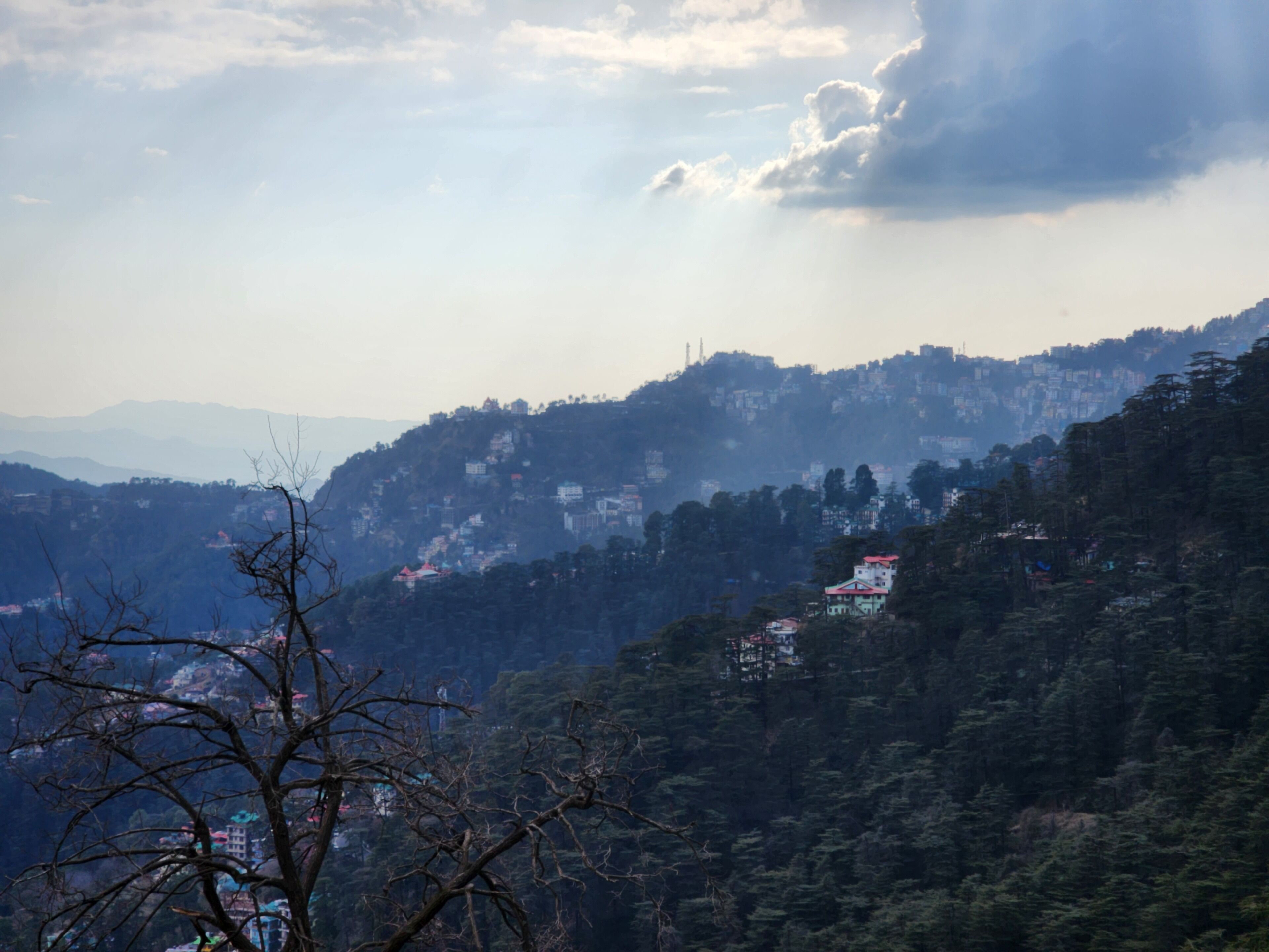Paisatge de muntanyes amb edificis dispersos i un bosc dens.