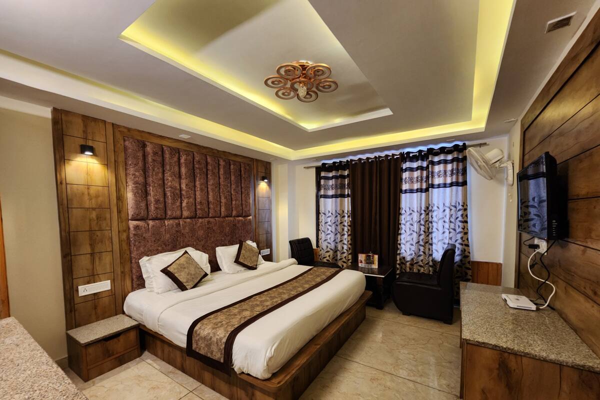 A modern bedroom with a large bed, wooden headboard, and a built-in TV.