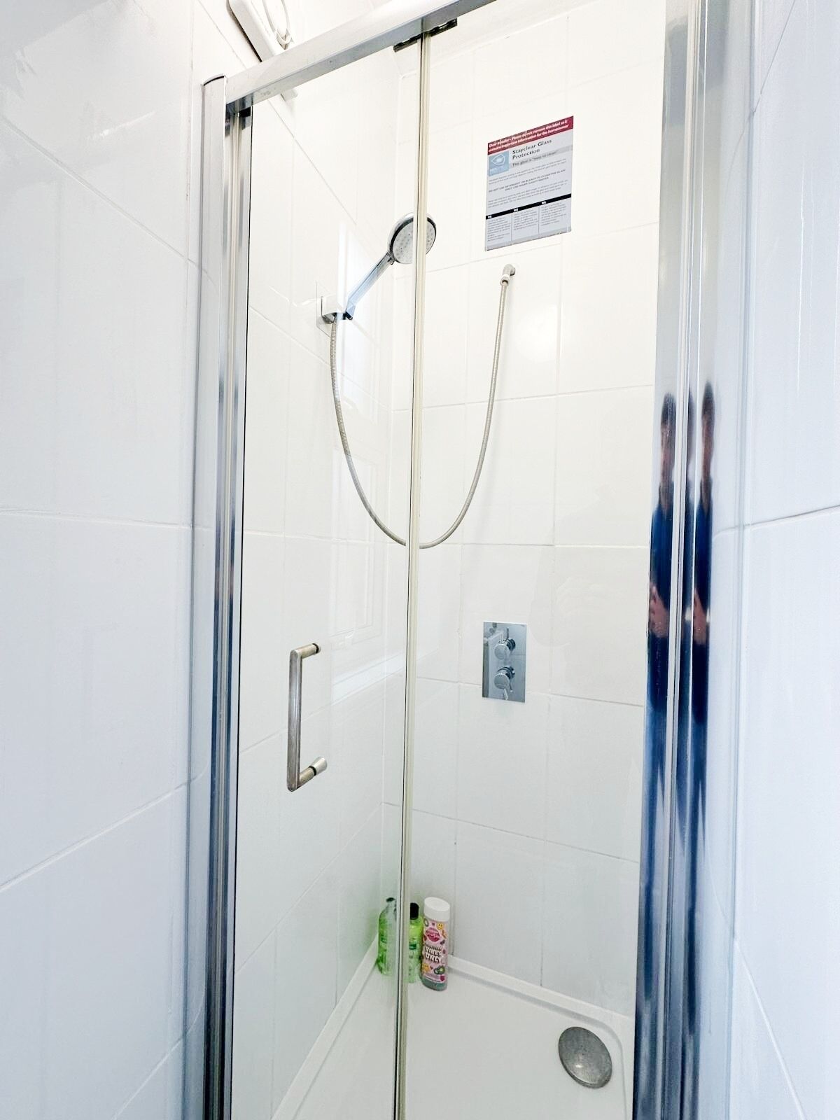 A glass-enclosed shower stall with a handheld showerhead and a wall-mounted faucet.