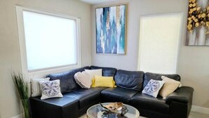 A modern living room with a sectional sofa, a glass coffee table, and a cowhide rug. - Adorable Downtown Mesa Cottage (Mesa)
