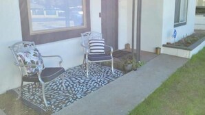 A house with a porch, two chairs, a patterned rug, and a small garden area. - Adorable Downtown Mesa Cottage (Mesa)