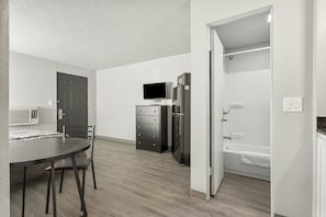 Una cocina moderna con mesa de comedor, sillas, televisor y electrodomésticos integrados.