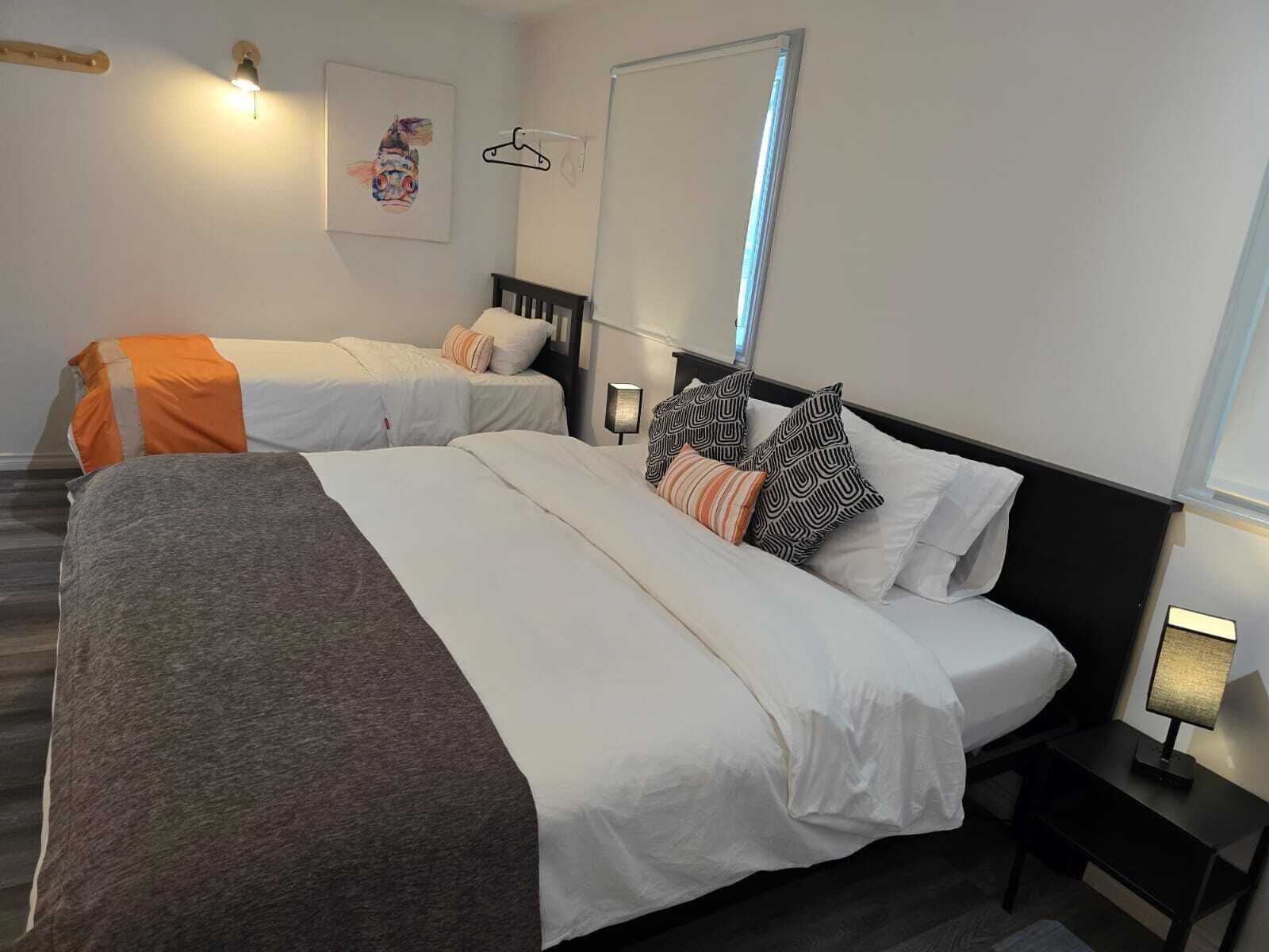Ein Hotelzimmer mit zwei Betten, einem großen Spiegel, einer Pendelleuchte und einem Nachttisch mit Lampe.