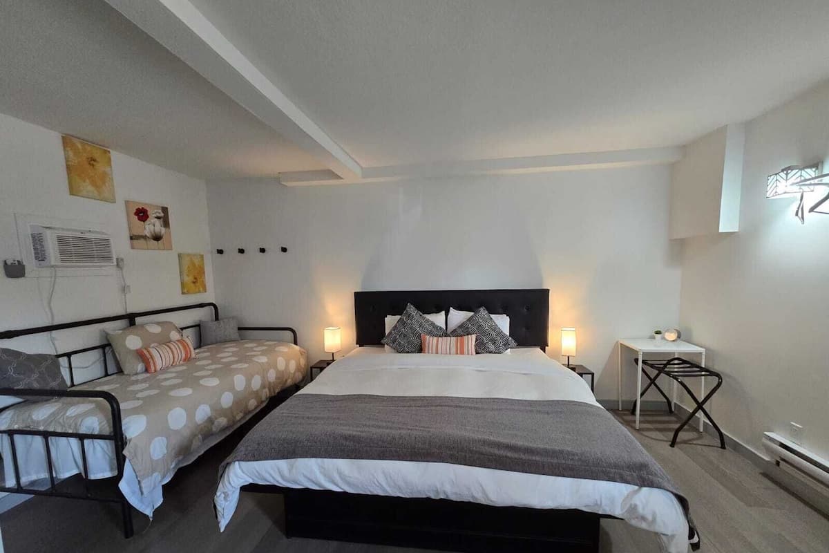 A bedroom with a large bed, a smaller bed, a desk, and a chair.
