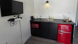 A modern kitchen with a flat-screen TV, a coffee maker, a sink, and a red refrigerator.