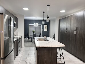 Una cocina moderna con gabinetes de madera oscura, electrodomésticos de acero inoxidable y encimera de mármol.