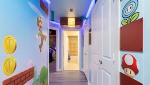 A hallway with Mario and Luigi wall art, a question mark sign, and a door with a Mario mushroom cutout. - Disney themed 3br condo (Kissimmee)