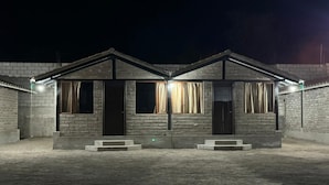 A building with a symmetrical facade, featuring a central door flanked by two windows with curtains.