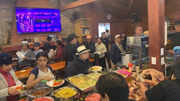 A buffet with various food items and people serving and eating.