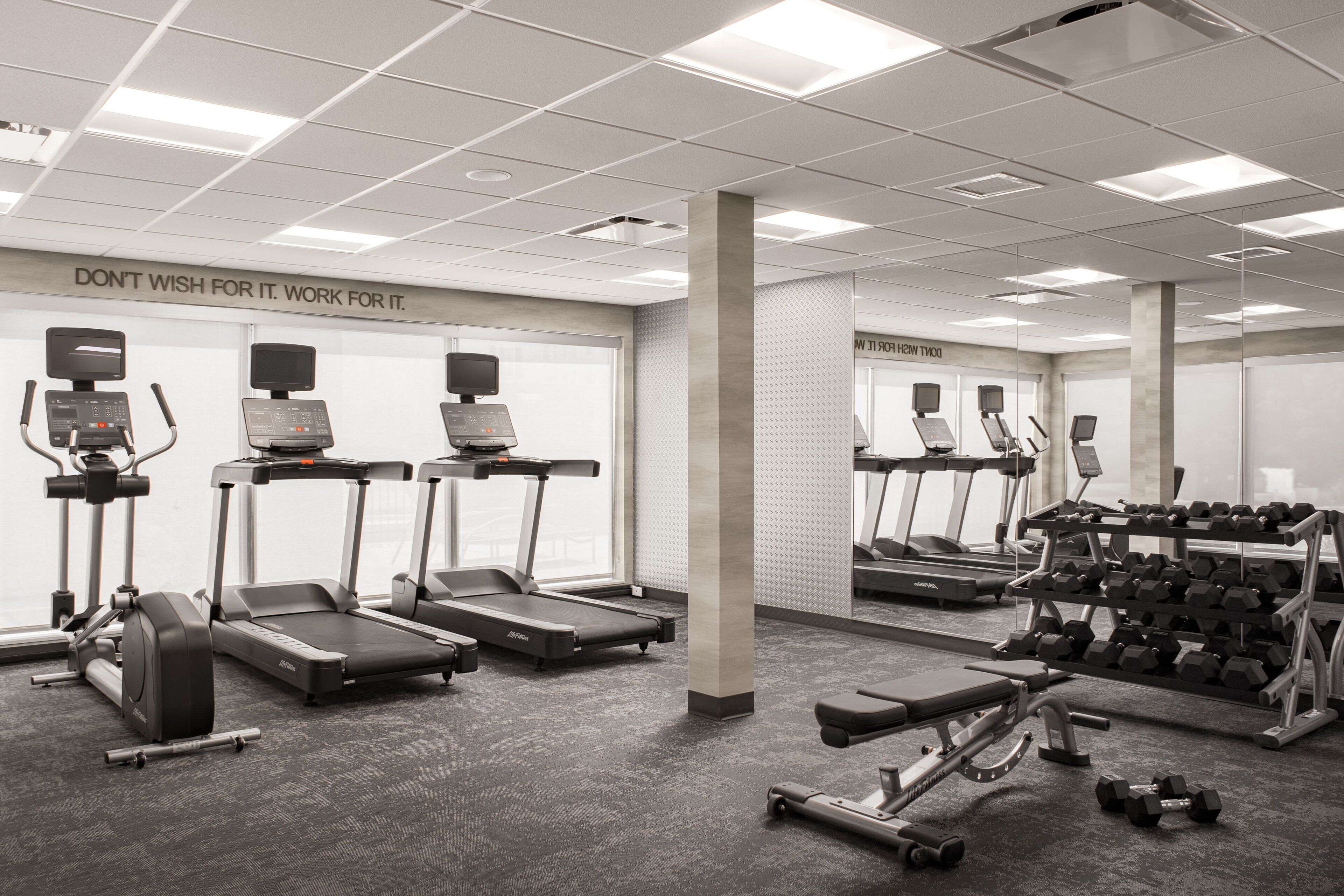 Une salle de sport équipée de tapis de course, d’haltères et d’appareils d’exercice.