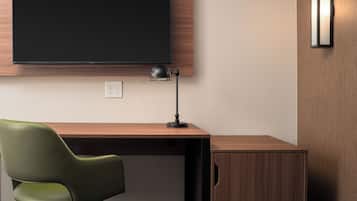 A modern office desk with a green chair, a black desk lamp, and a mounted flat-screen TV.