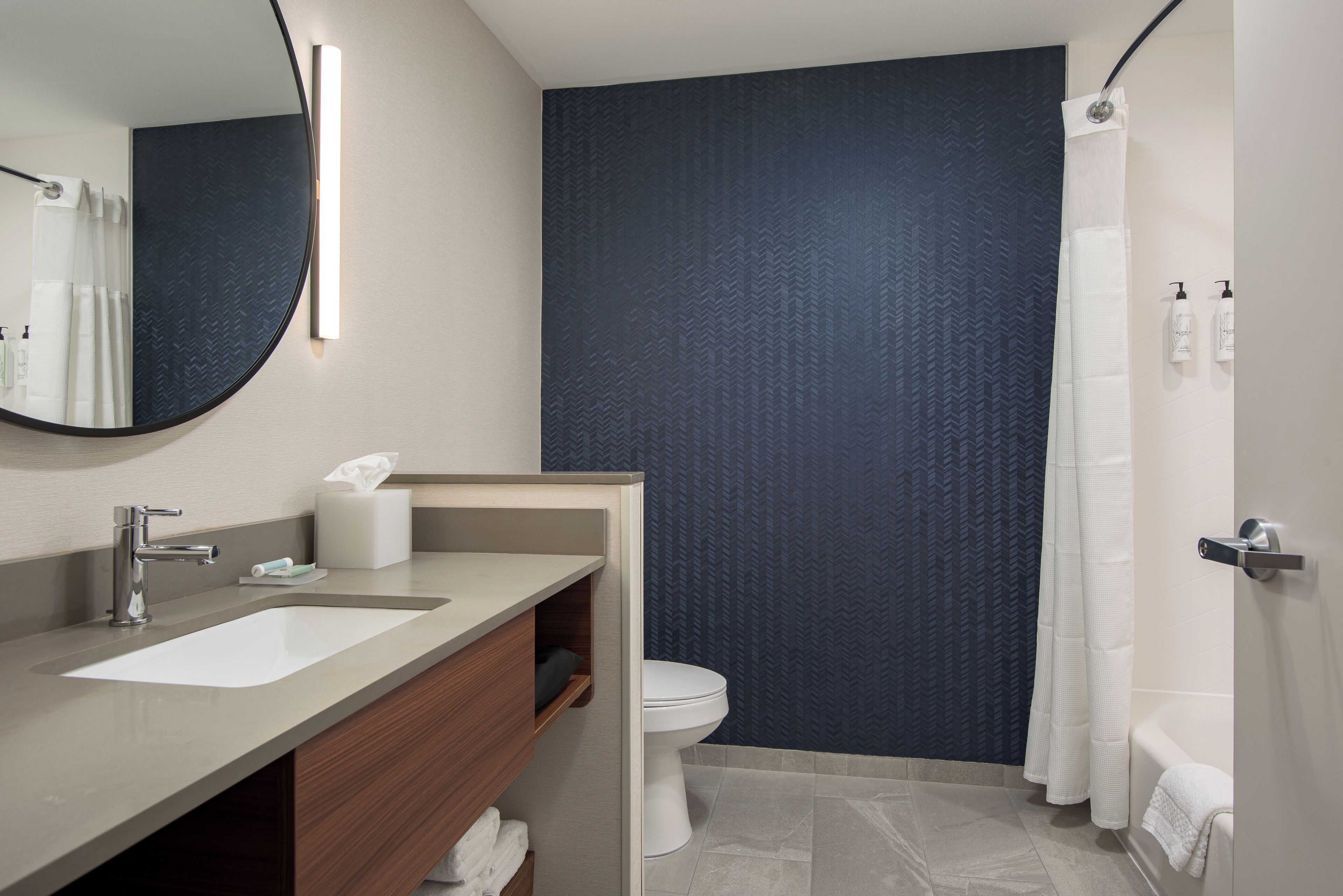 A modern bathroom with a large mirror, two sinks, a toilet, and a bathtub.