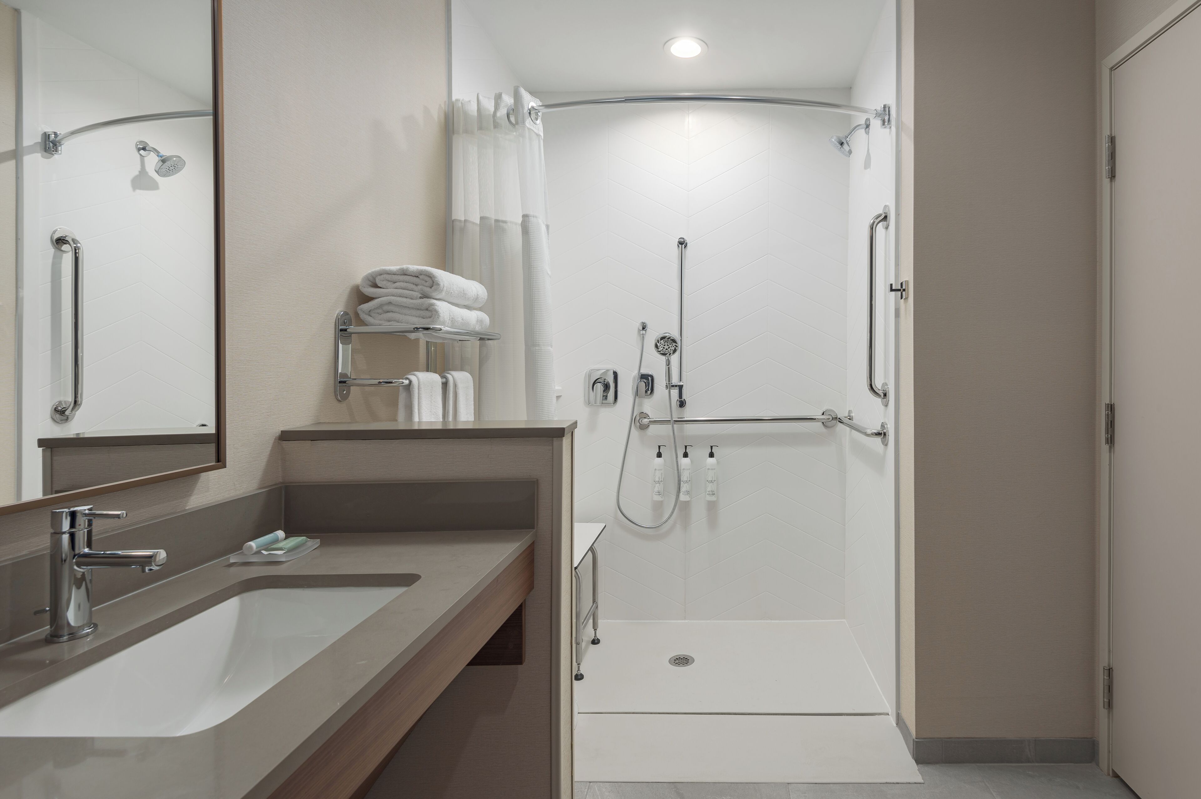 A modern bathroom with a large sink, a shower with a glass door, and a mirror.