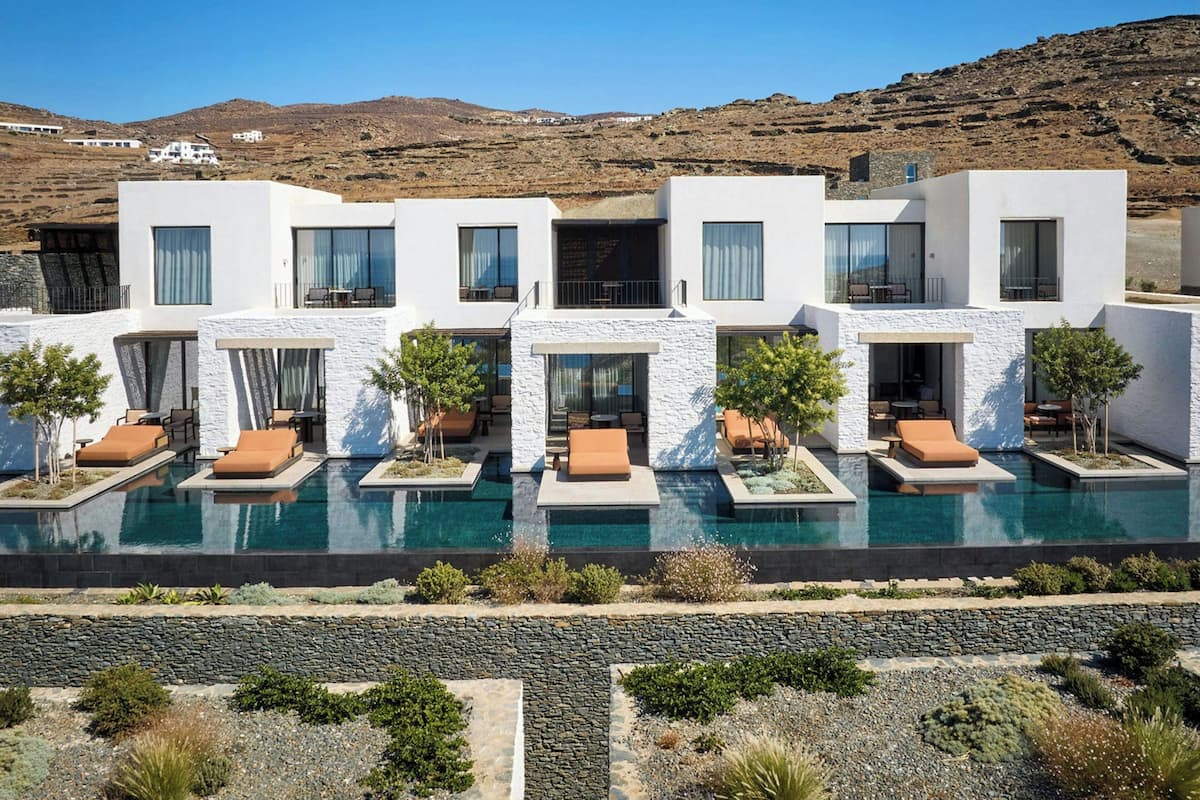 A modern resort with a pool, multiple rooms, and a mountainous backdrop.