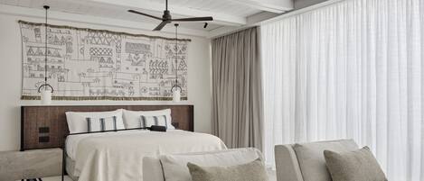 Una habitación de hotel moderna con cama, sofá y un ventanal con cortinas.