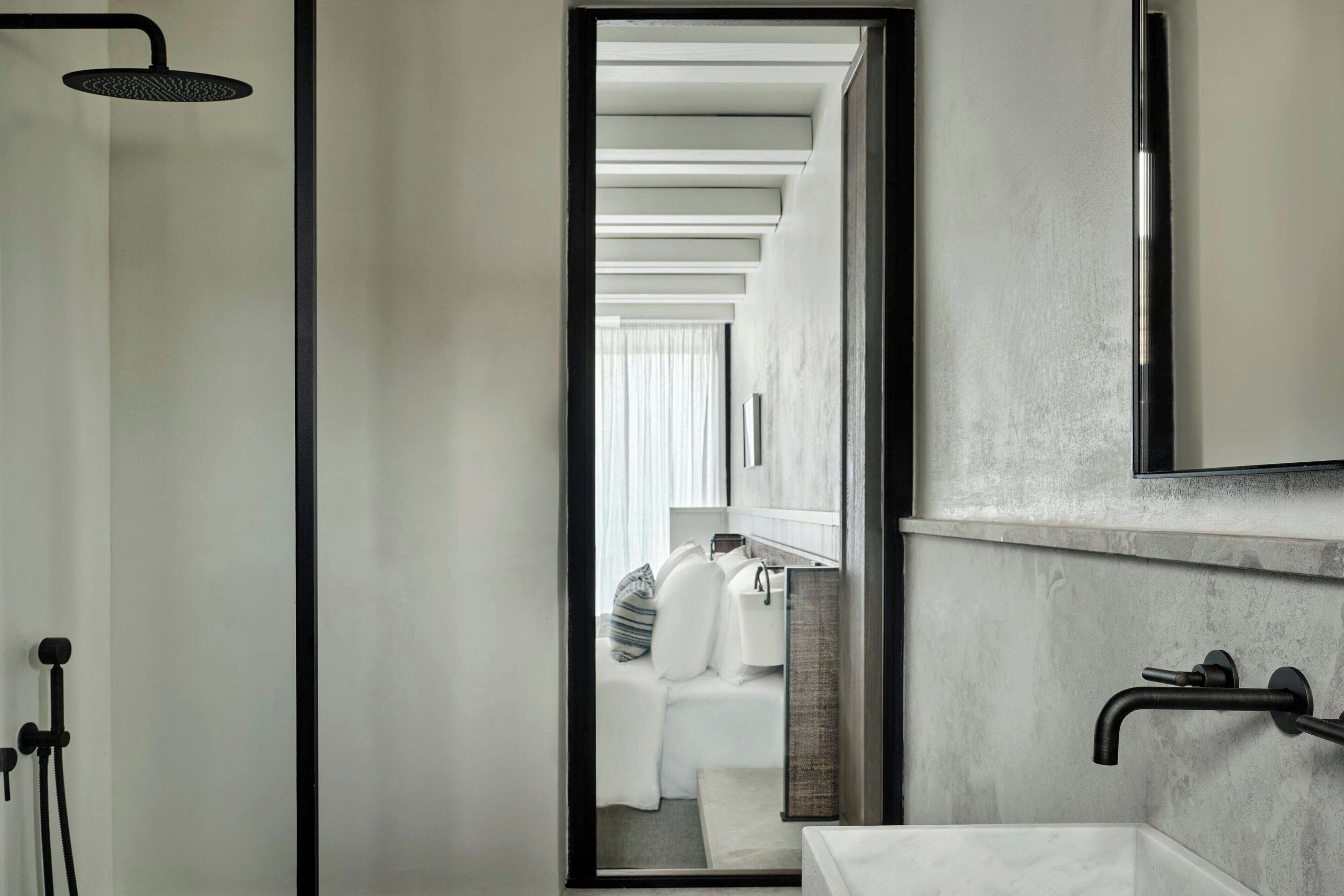 A modern bathroom with a large mirror, a showerhead, and a sink.