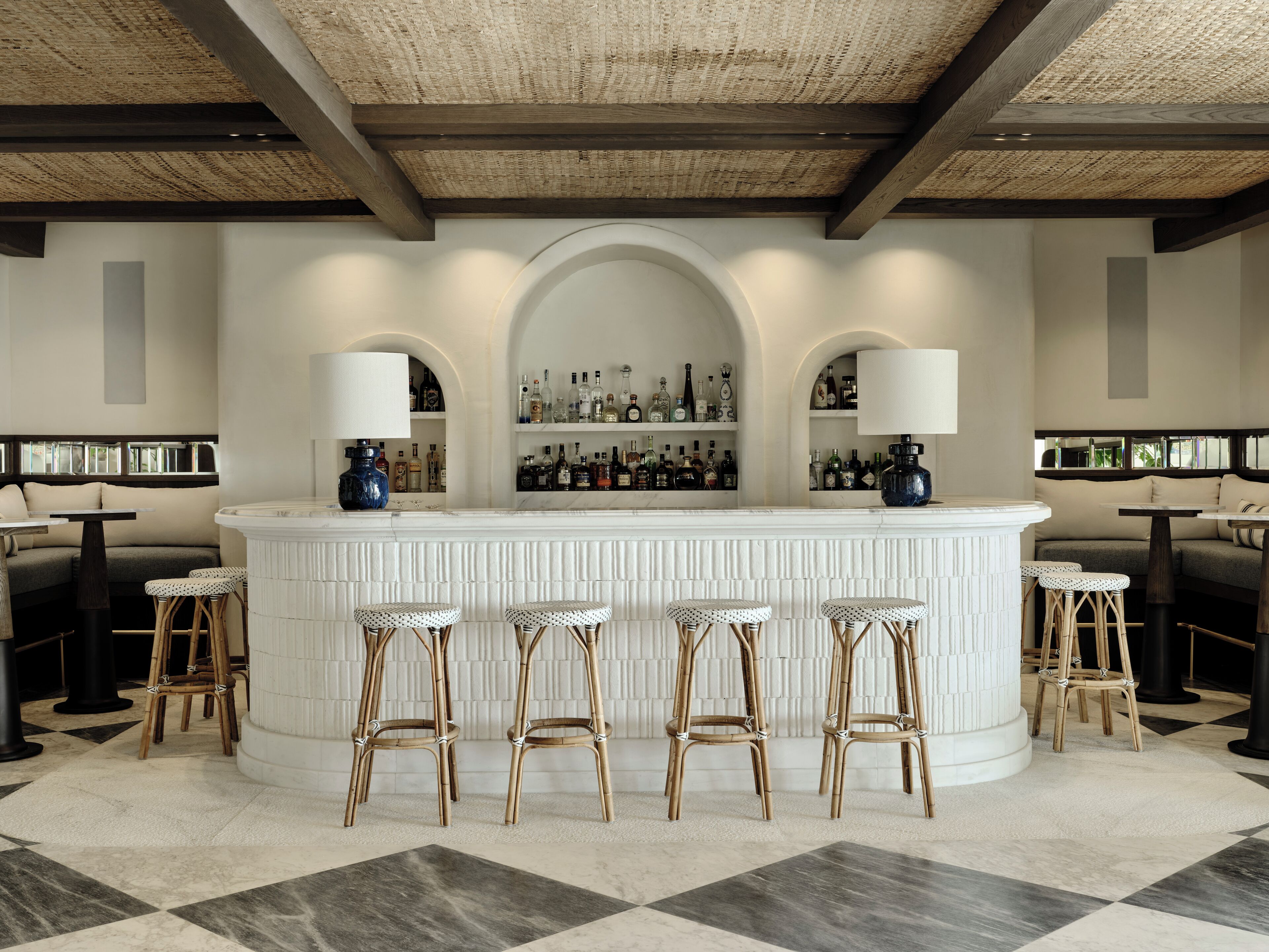 A bar area with a central island, bar stools, and shelves of bottles.