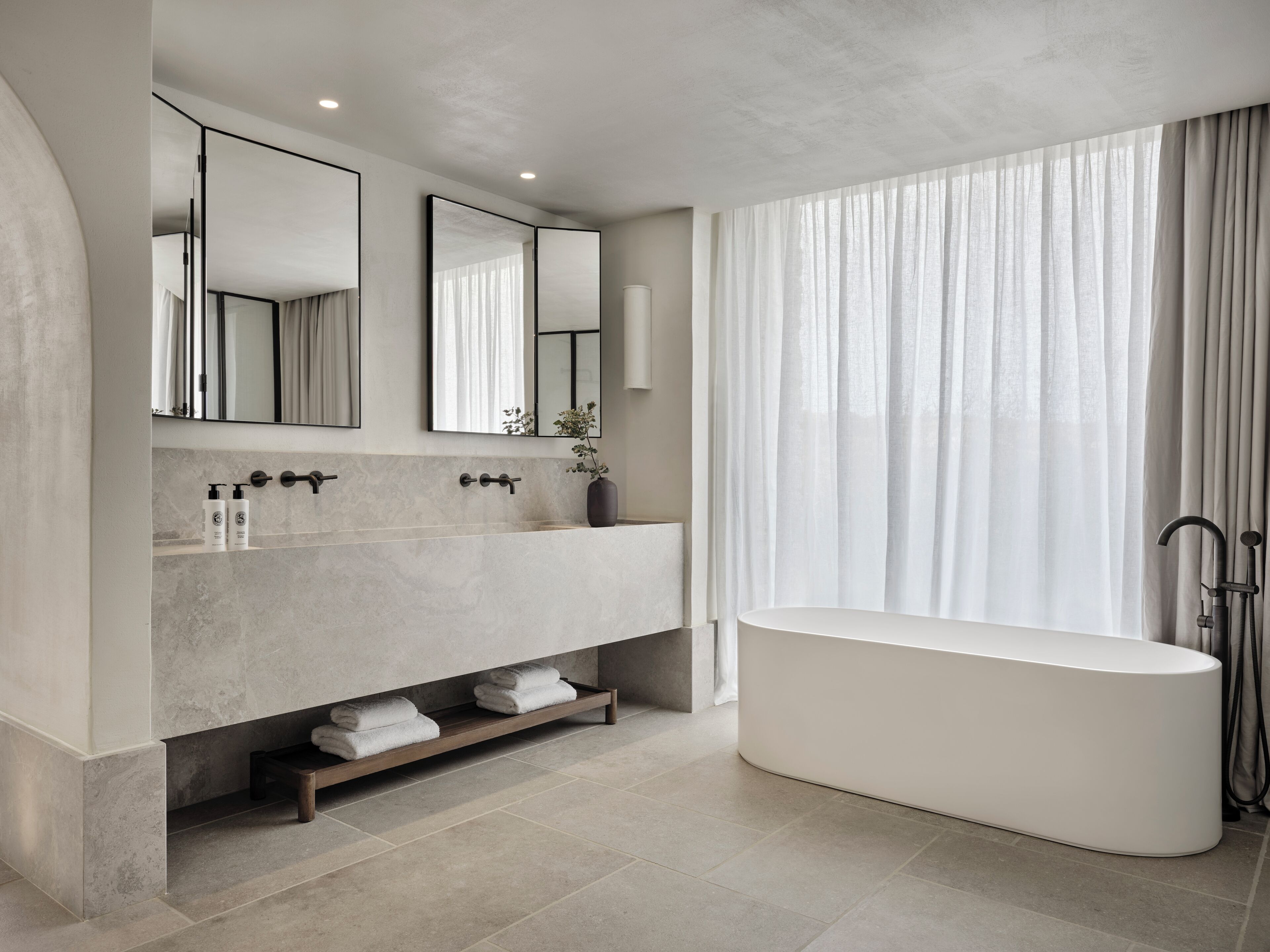 A modern bathroom with a freestanding bathtub, a large mirror, and a vanity with a marble countertop.