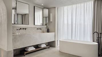 A modern bathroom with a freestanding bathtub, a large mirror, and a vanity with a marble countertop.