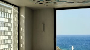 A modern room with a large window overlooking the sea, a minimalist design, and a view of the ocean. - Odera, Tinos, Autograph Collection (Tinos)
