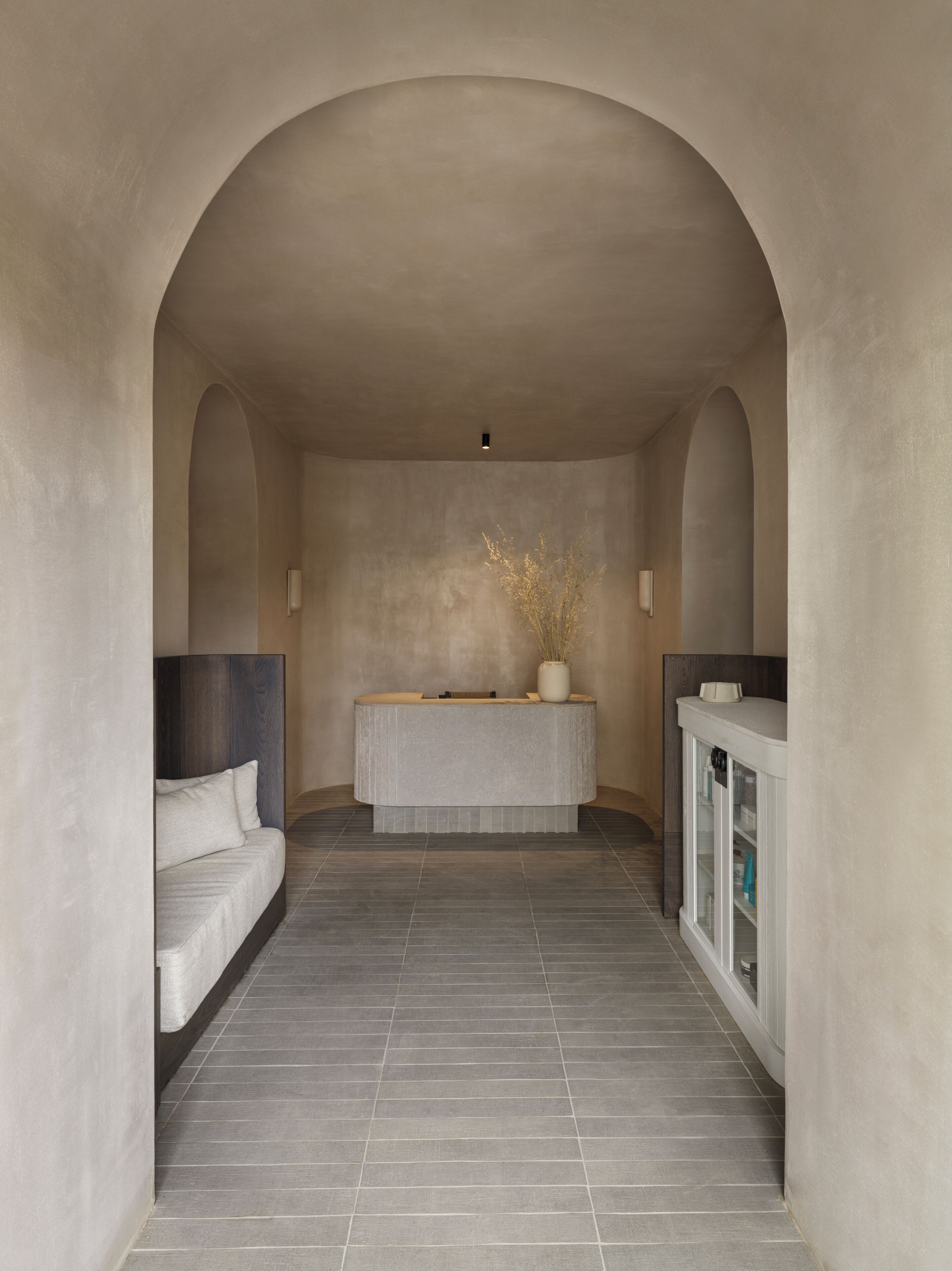 A modern bathroom with a freestanding bathtub, a bench, and a cabinet with toiletries.