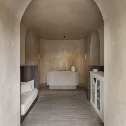 A modern bathroom with a freestanding bathtub, a bench, and a cabinet with toiletries.