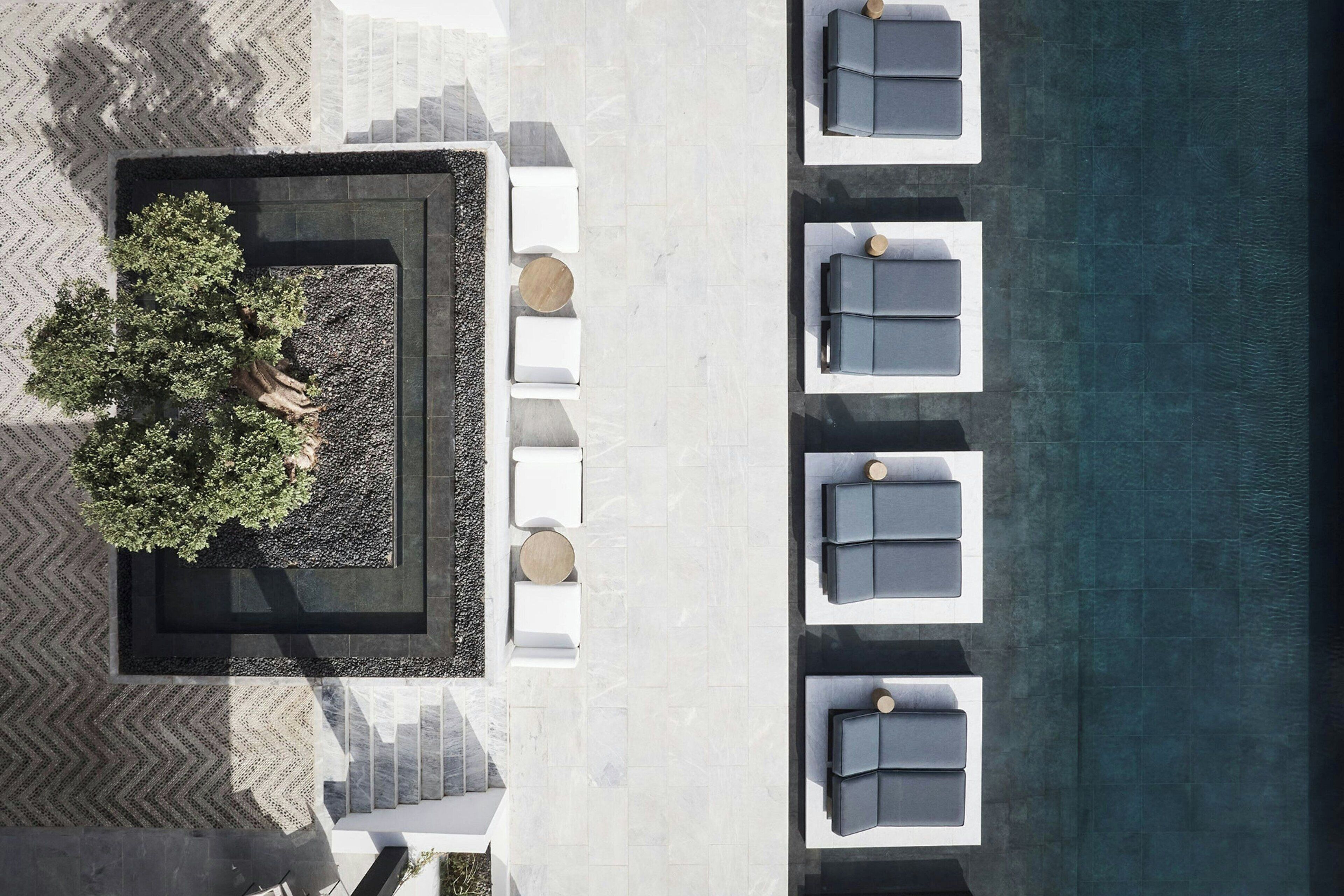 An aerial view of a poolside area with white lounge chairs, a small garden, and a staircase leading to an upper level.