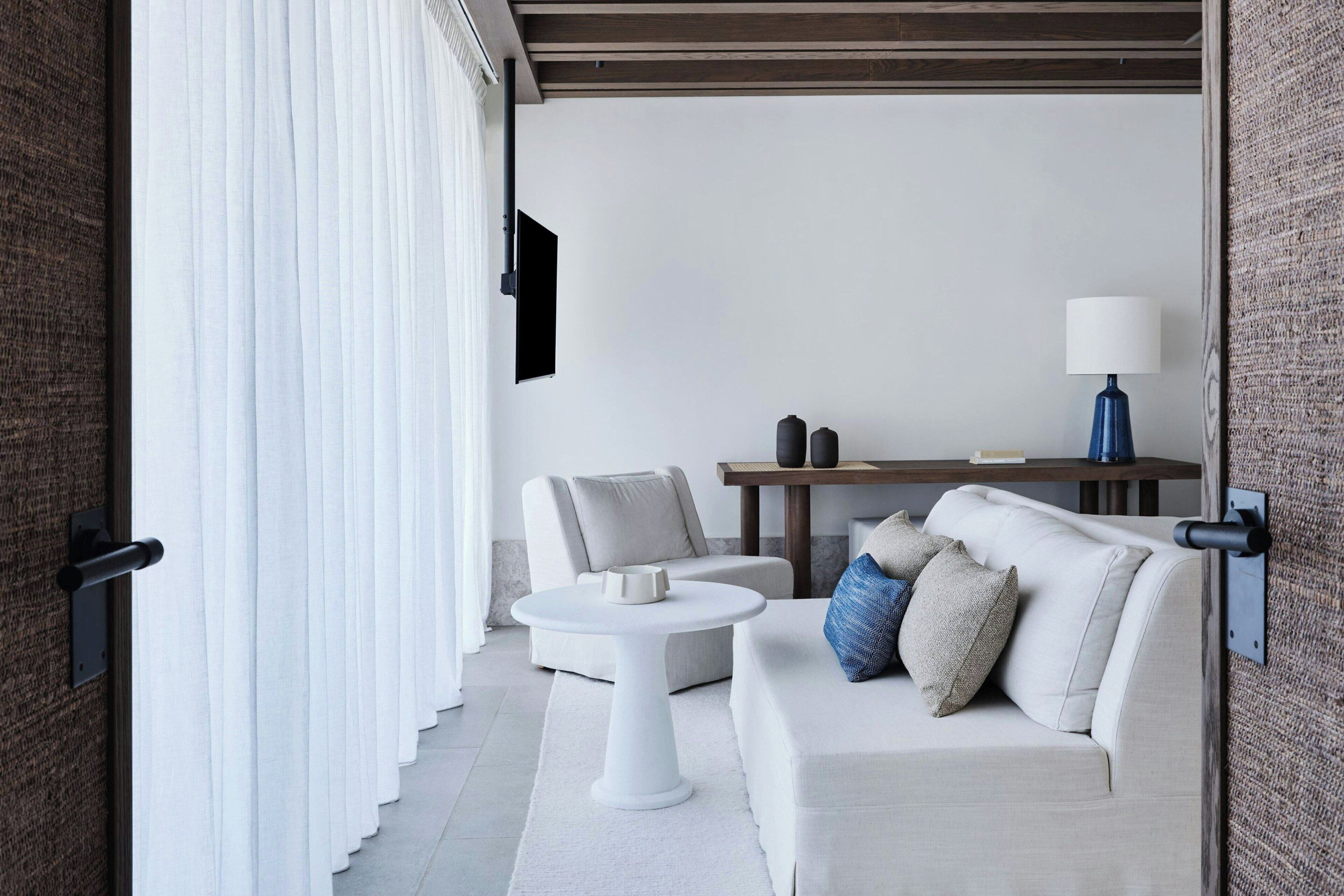 A modern living room with a sofa, a small round table, and a lamp.