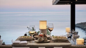 A table set for a meal with a view of the sea, a lamp, and wine glasses. - Odera, Tinos, Autograph Collection (Tinos)