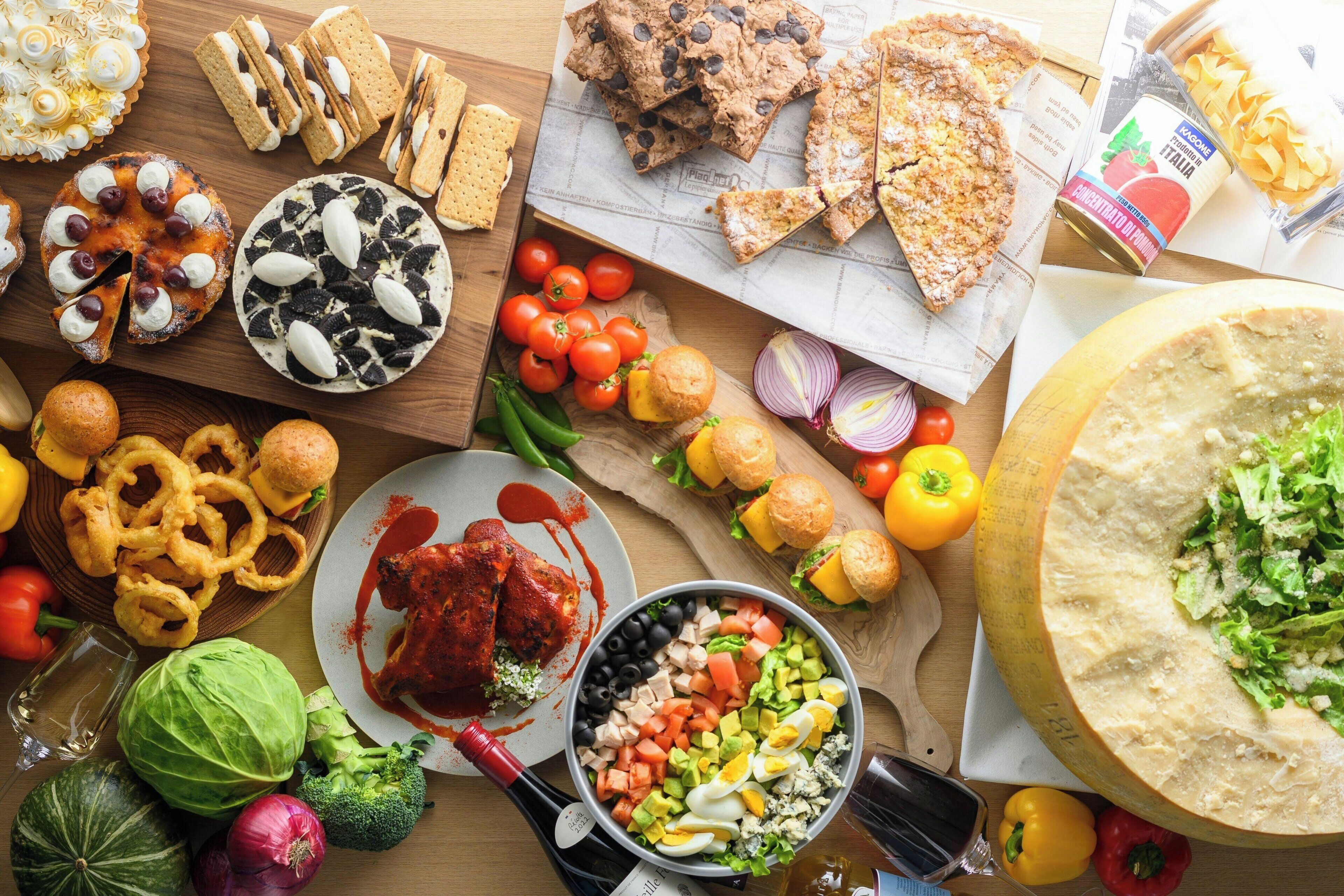 Variedad de alimentos, incluyendo pizza, ensalada y pan, sobre una mesa de madera.