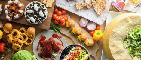 Variedad de alimentos, incluyendo pizza, ensalada y pan, sobre una mesa de madera.