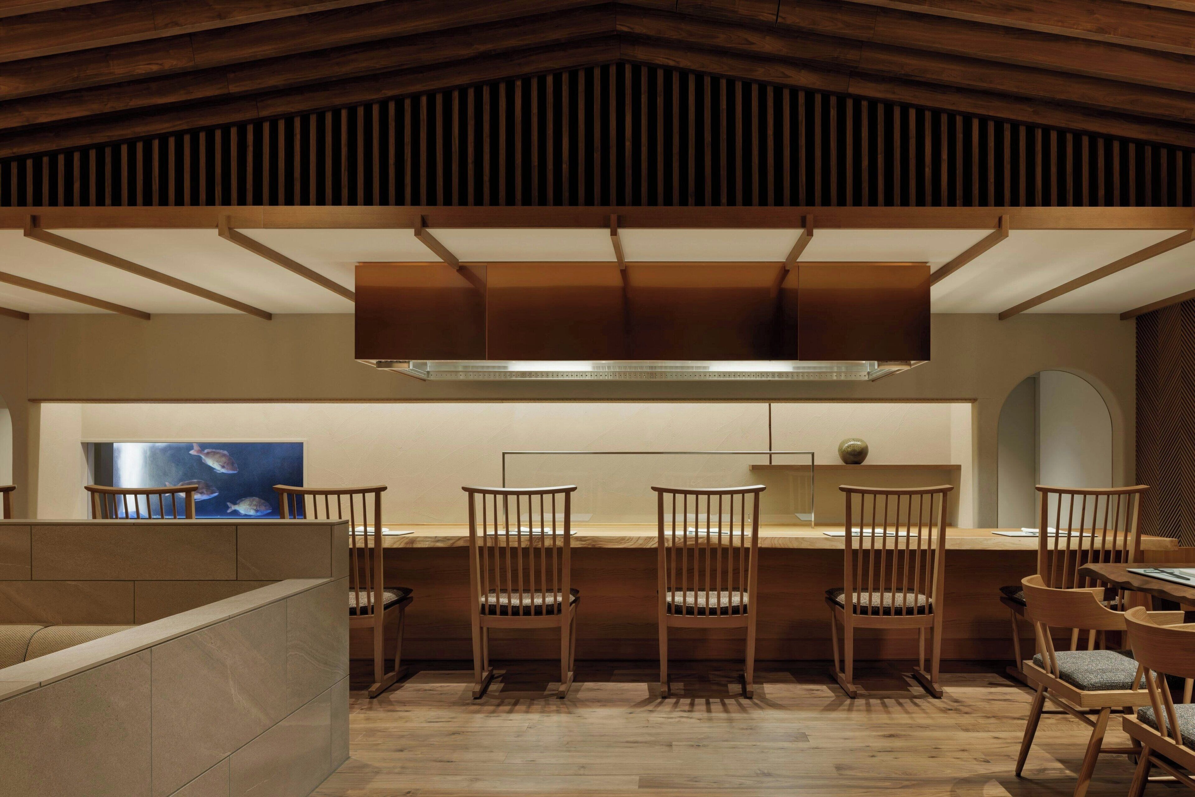 Una cocina moderna con sillas de madera, una isla grande y vistas de peces al fondo.