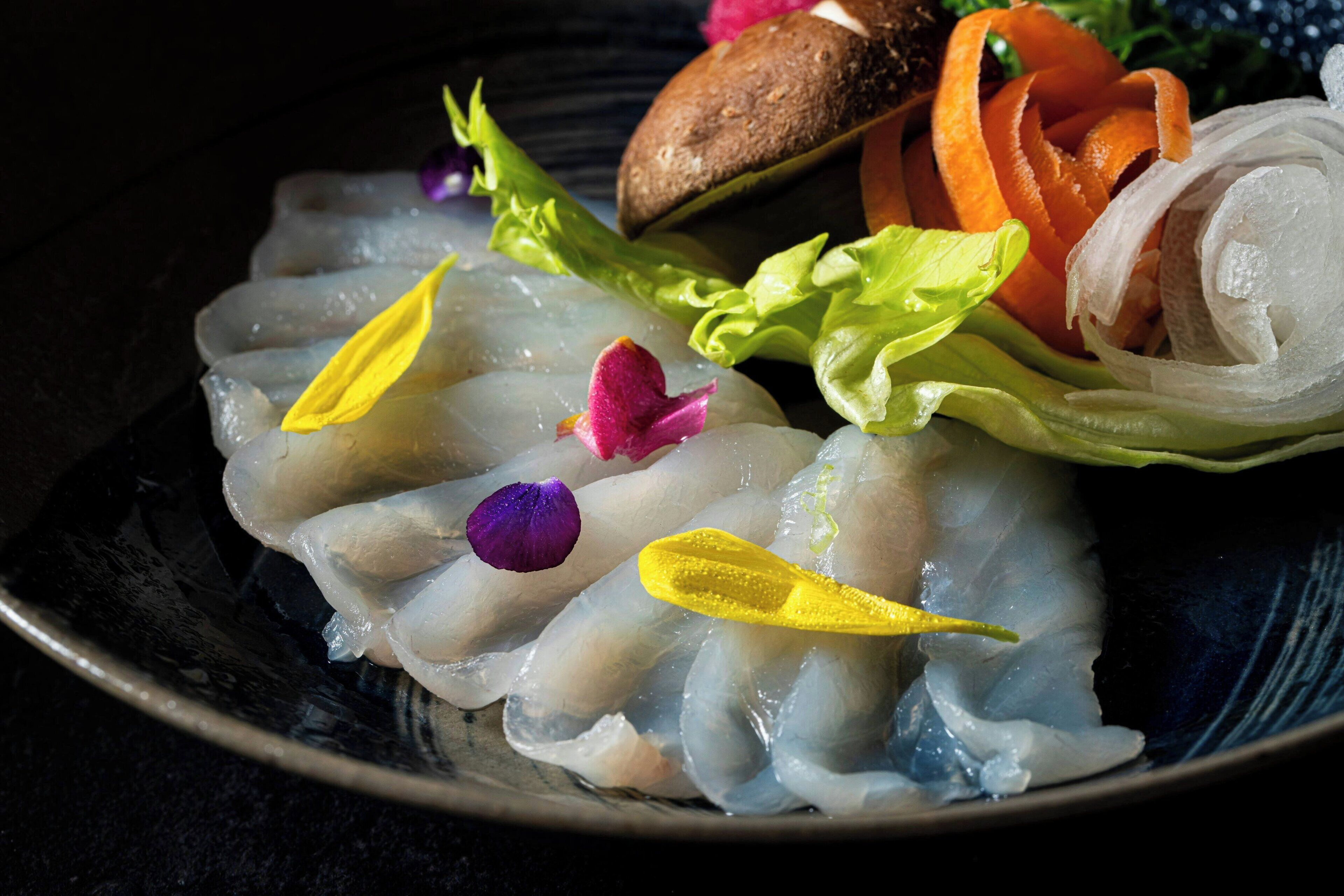 A plate of sashimi with garnishes and vegetables.