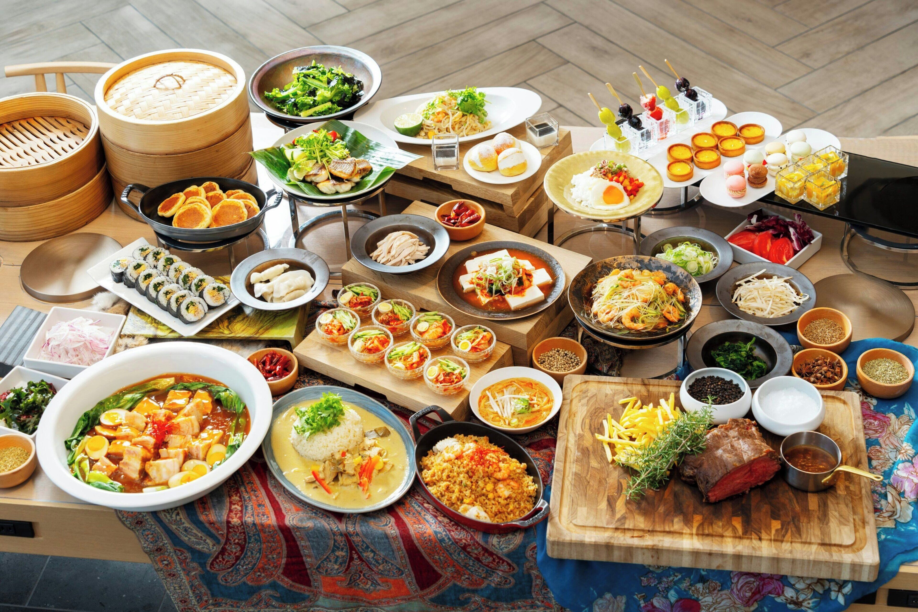 A table with various dishes, including sushi, dumplings, and a variety of Asian cuisine.