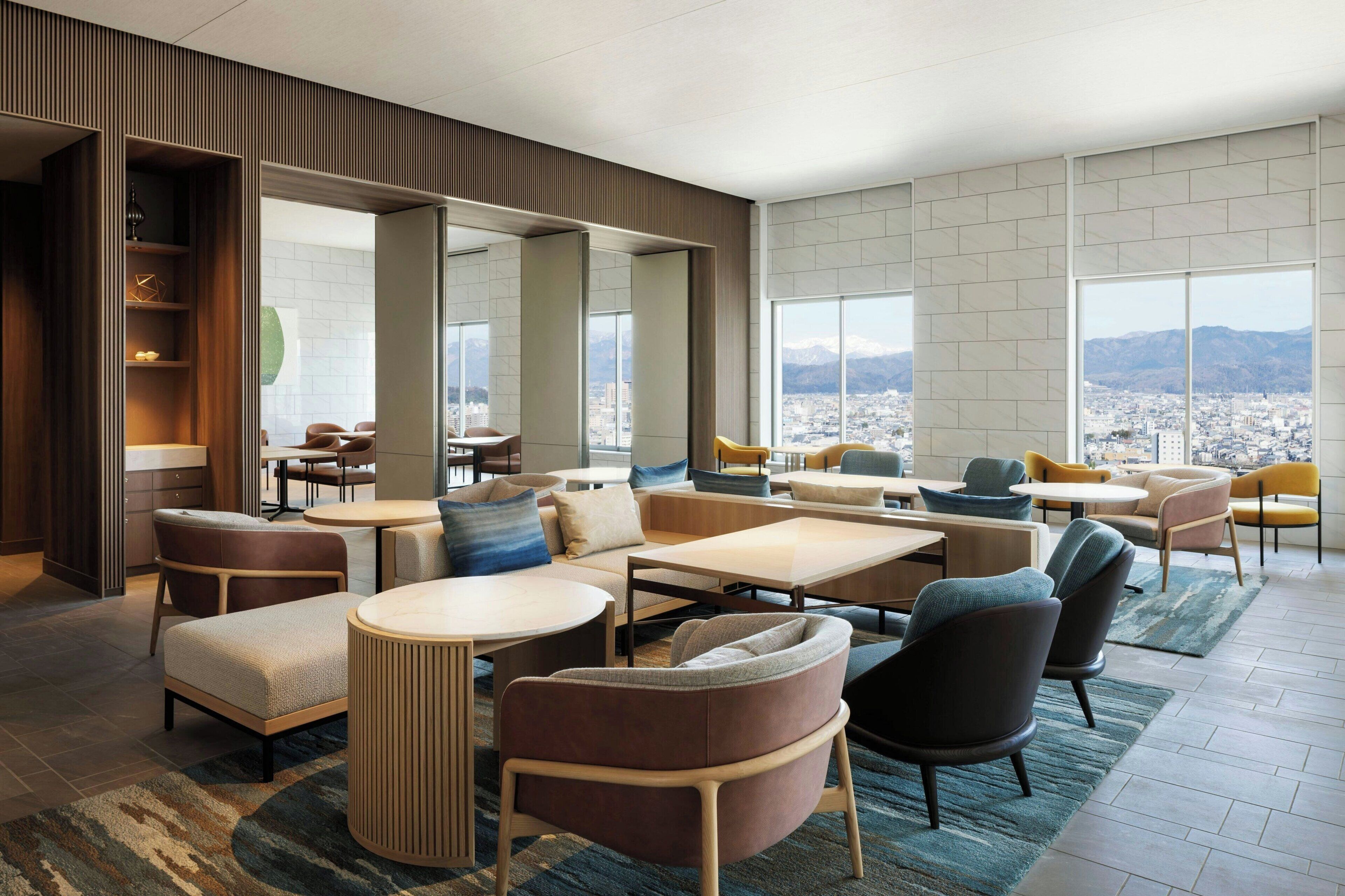 Eine moderne Hotelhalle mit Sitzgelegenheit, großen Fenstern und Blick auf die Stadt.