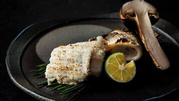 A plate with grilled fish, a slice of lime, and a mushroom.