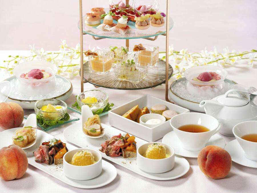Una variedad de alimentos y bebidas sobre una mesa, incluyendo frutas, postres y té.